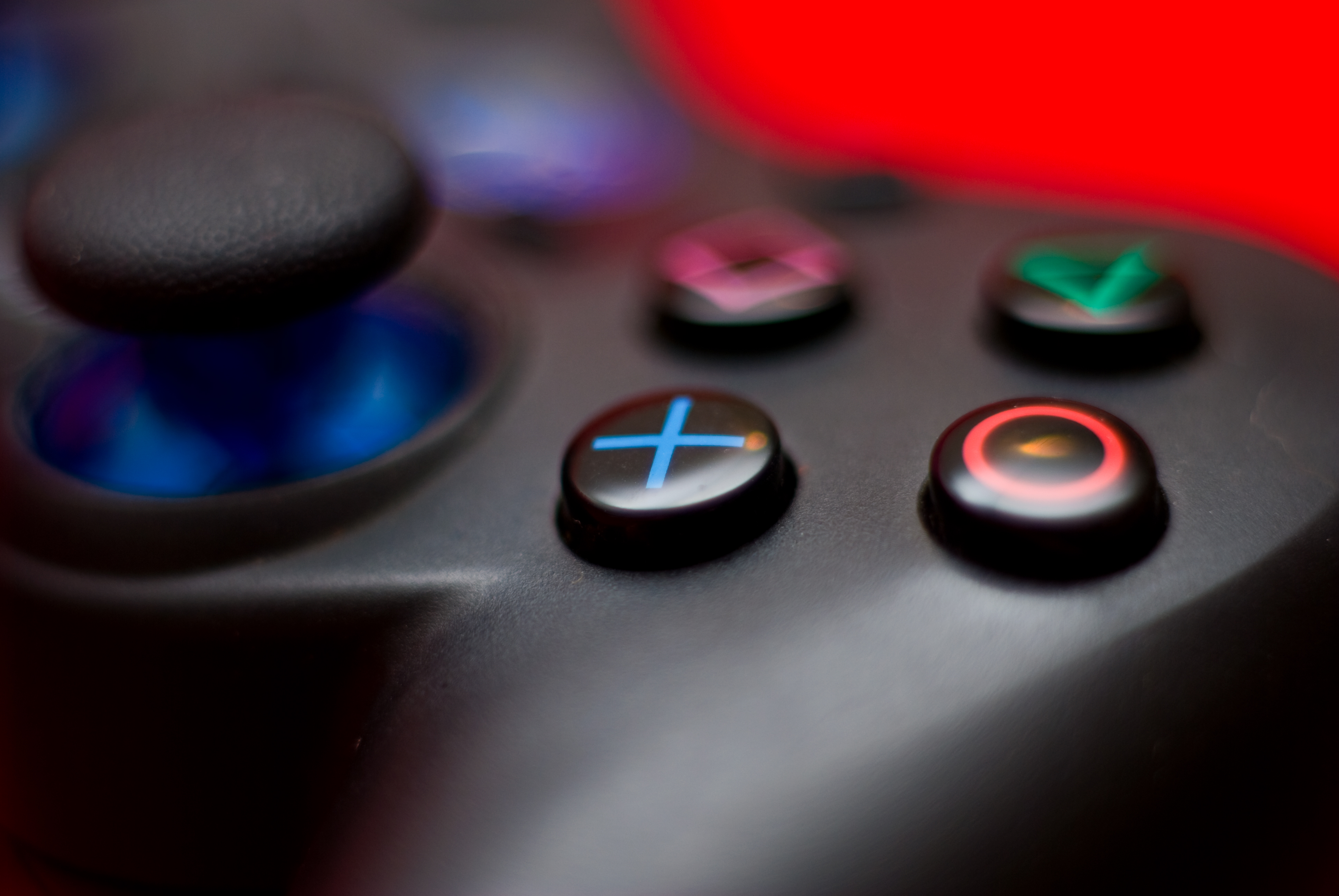 Closeup of a PlayStation controller, showing four buttons and a joystick